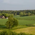 Landschaft bei Hasbergen Fachwerkhaus am Waldrand, umgeben von weiten, grünen Feldern und sanften Hügeln.