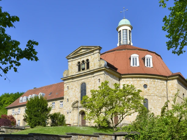 Kirche mit oktogonalem Turm, blauer Kuppel und Steinmauer an sonnigem, klaren Tag.