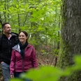 Wandern im Teutoburger Wald Zwei Personen spazieren auf einem Waldweg, umgeben von grünem Laub.