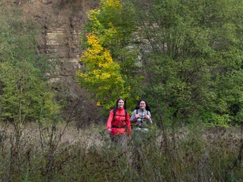 Steilwand Zwei Wanderinnen mit bunten Rucksäcken vor einer bewaldeten Felswand und herbstlichen Bäumen.Two female hikers with colorful rucksacks in front of a wooded rock face and autumnal trees.To kvindelige vandrere med farverige rygsække foran en skovklædt klippevæg og efterårstræer.Twee vrouwelijke wandelaars met kleurrijke rugzakken voor een beboste rotswand en herfstbomen.