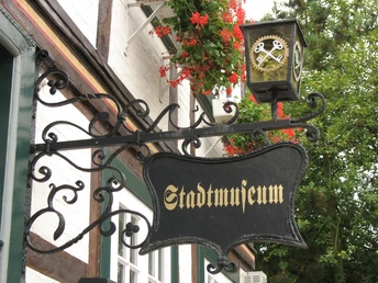 Stadtmuseum Quakenbrück Metallschild mit der Aufschrift "Stadtmuseum" vor einem Fachwerkgebäude.