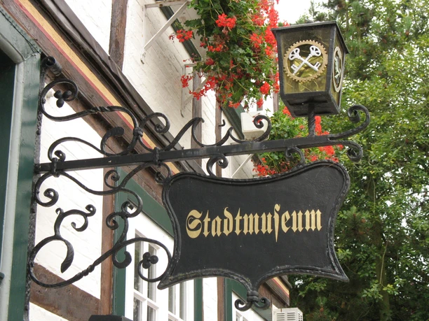 Stadtmuseum Quakenbrück Metallschild mit der Aufschrift "Stadtmuseum" vor einem Fachwerkgebäude.