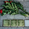 Stolpersteine Quakenbrück.jpg Drei Stolpersteine für die Familie Nebilum, umgeben von Blumen auf Pflastersteinen.