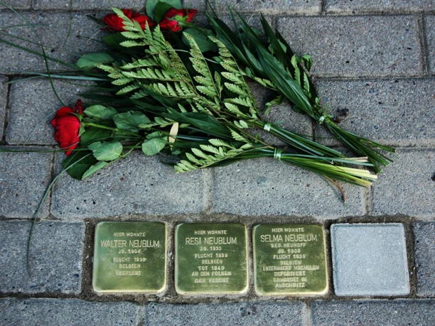 Stolpersteine Quakenbrück.jpg Drei Stolpersteine für die Familie Nebilum, umgeben von Blumen auf Pflastersteinen.