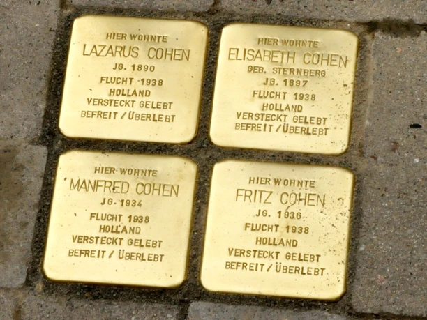 Stolpersteine Quakenbrück.jpg Vier goldene Stolpersteine auf Gehweg, die jüdische NS-Opfer ehren.