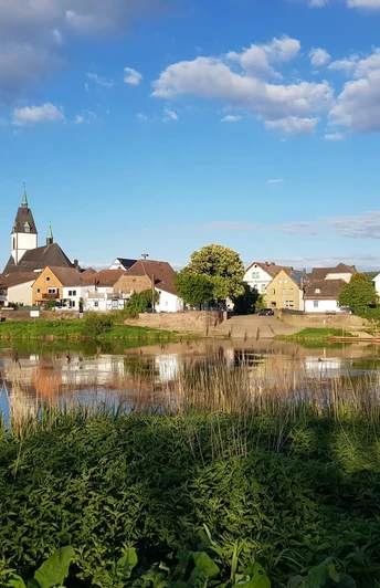 5_weserradweg_blickaufluechtringen_hx2_stephanberg Blick auf das malerische Lüchtringen mit Kirche, Fachwerkhäusern und der Weser im Vordergrund.