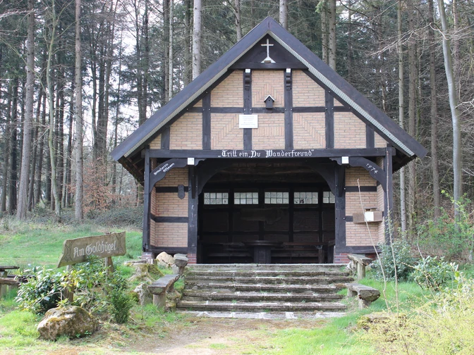 Waldbrauereiunterstand aus Holz und Ziegeln, umgeben von hohen Bäumen, mit hölzernem Zugang.Forest brewery shelter made of wood and bricks, surrounded by tall trees, with wooden access.Skovbryggeriets shelter er lavet af træ og mursten, omgivet af høje træer og med adgang i træ.Bosbrouwerijhuis van hout en bakstenen, omringd door hoge bomen, met houten toegang.
