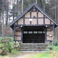 Schutzhütte auf dem Heiligenberg Waldbrauereiunterstand aus Holz und Ziegeln, umgeben von hohen Bäumen, mit hölzernem Zugang.