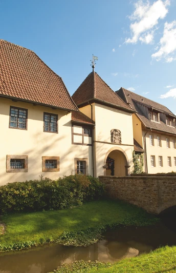 Historisches Gebäude mit Fachwerk, umgeben von gepflegtem Garten und einem kleinen Wasserlauf.Historic half-timbered building surrounded by a well-kept garden and a small stream.Historisk bindingsværksbygning omgivet af en velplejet have og et lille vandløb.Historisch vakwerkhuis omringd door een verzorgde tuin en een beekje.
