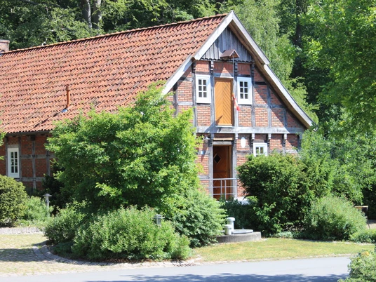 Heimathaus Feldmühle Fachwerkhaus aus Backstein im Grünen mit roten Ziegeldach und umgebender Pflanzenwelt.Half-timbered brick house in a green setting with red tiled roof and surrounding vegetation.Bindingsværkshus i mursten på landet med rødt tegltag og omgivende vegetation.Vakwerkhuis van baksteen op het platteland met rood pannendak en omringende vegetatie.