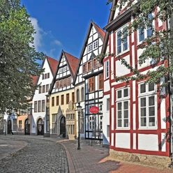 Mindener Museum Fachwerkhäuser in einer historischen Straße mit Kopfsteinpflaster und blauen Himmel im Hintergrund.