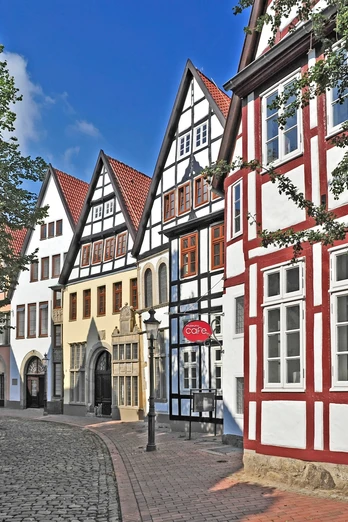 Mindener Museum Fachwerkhäuser in einer historischen Straße mit Kopfsteinpflaster und blauen Himmel im Hintergrund.