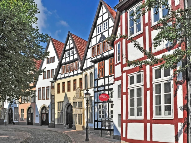 Mindener Museum Fachwerkhäuser in einer historischen Straße mit Kopfsteinpflaster und blauen Himmel im Hintergrund.