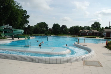 Freizeitbad Hunteholz Das Freizeitbad Hunteholz mit Außenbecken, Strömungskanal und einer grünen Wasserrutsche.