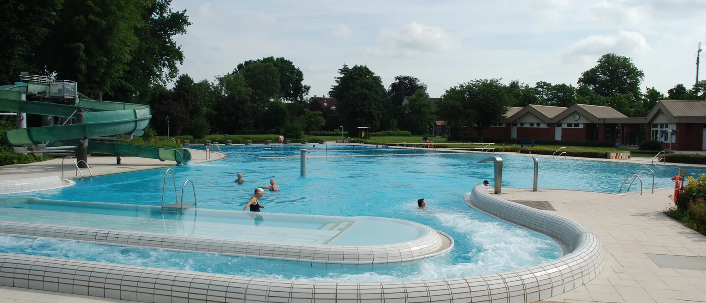 Freizeitbad Hunteholz Das Freizeitbad Hunteholz mit Außenbecken, Strömungskanal und einer grünen Wasserrutsche.
