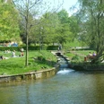 Grünes Stadtareal mit Bachlauf, Wiesen und Spaziergängern im westlichen Paderquellgebiet.