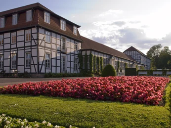 Historisches Fachwerkgebäude mit blühendem Blumenbeet im Gräflichen Park von Bad Driburg bei Sonnenschein.