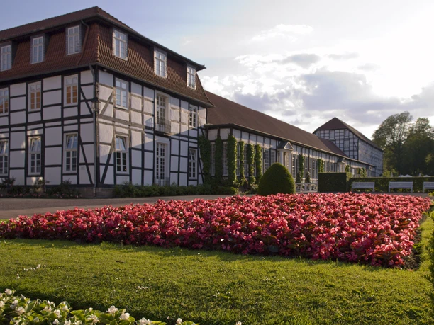 Historisches Fachwerkgebäude mit blühendem Blumenbeet im Gräflichen Park von Bad Driburg bei Sonnenschein.