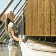 Tief durchatmen am Gradierwerk Eine Frau lehnt lächelnd an einem hölzernen Gradierwerk, das mit herabfließender Sole benetzt ist.