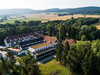 HolsingVital im Wiehengebirge Luftaufnahme eines weitläufigen Gebäudekomplexes umgeben von Wald und Feldern im Wiehengebirge.