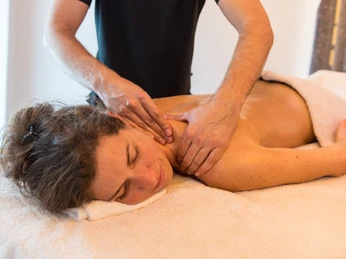 Massage zur Entspannung Eine Frau erhält eine entspannende Massage auf einer Liege, während ein Masseur ihren Nacken bearbeitet.