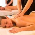 Entspannende Massage im H2O Herford Zwei Personen genießen entspannende Rückenmassagen auf Massageliegen in einem Wellnessbereich.