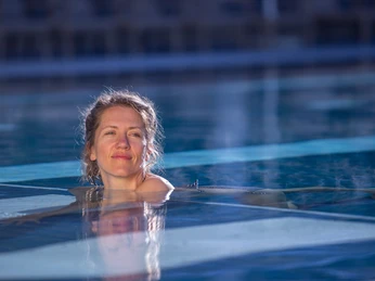 Zeit für Mädels Eine Frau genießt entspannt das warme Wasser eines Pools, umgeben von ruhiger, blauer Umgebung.
