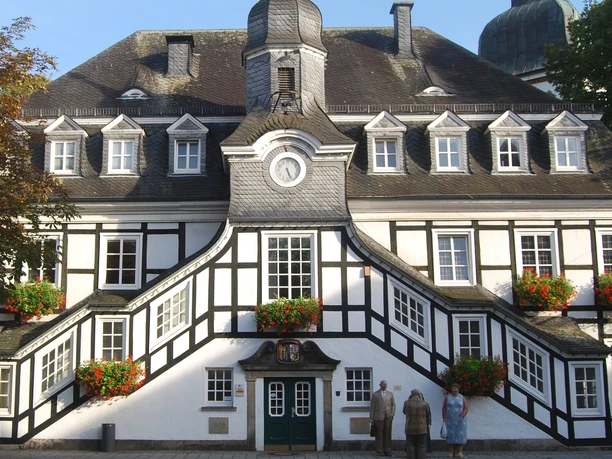 Fachwerk-Rathaus von Rietberg mit symmetrischen Treppenaufgängen, Verzierungen und Blumendekorationen.