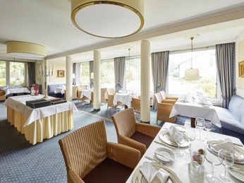 Hotel Bärenstein - Restaurant Helles Restaurant im Hotel Bärenstein mit eingedeckten Tischen, großen Fenstern und Rattanmöbeln.