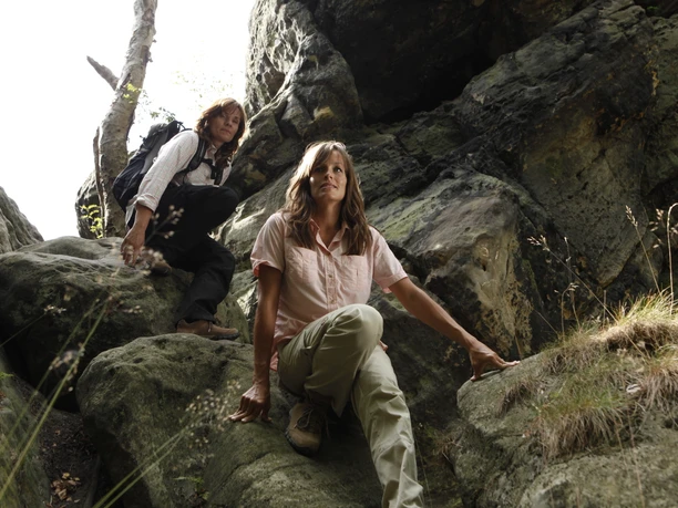 Dörenther Klippen Zwei Personen klettern in felsiger Schlucht der Dörenther Klippen, umgeben von steilen Felsen.