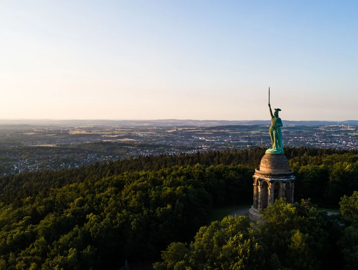 Hermannsdenkmal Hermannsdenkmal in einem bewaldeten Hügelplateau mit Blick auf die weitläufige Landschaft im Hintergrund.