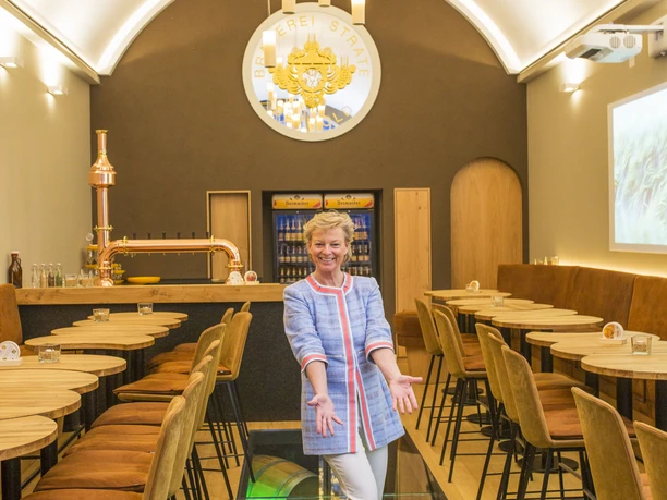 Frau Strate in der Stratosphäre Eine Frau steht in einem modernen, stilvoll eingerichteten Restaurant mit einem Glasboden.