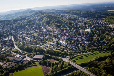 Luftaufnahme von Oerlinghausen mit grünen Hügeln, dichter Bebauung und umliegenden Wäldern bei Sonnenschein.