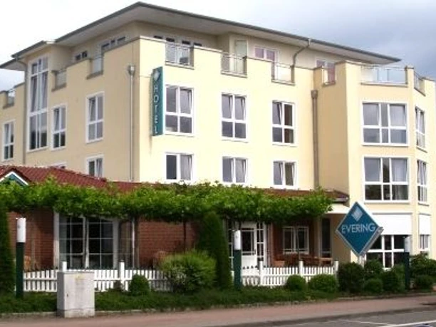 Akzent-Hotel_Landgasthof_Evering_-_Aussenansicht_-_Gastro.JPG Mehrstöckiges Hotelgebäude mit Restaurantbereich, heller Fassade, begrüntem Eingang und Straßenseite.