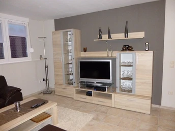 Ferienwohnung_Meppen_010.JPG Modern eingerichtetes Wohnzimmer mit heller Wohnwand, Fernseher, Glastüren und Dekoration.