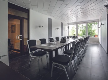Konferenzraum_-_Parkhotel_Papenburg.jpg Heller Konferenzraum mit langer Tischreihe, schwarzen Stühlen und großen Fenstern zum Park.
