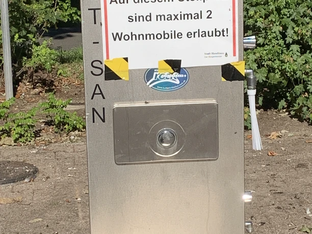 Womo Stellplatz Lingenerstr. 2 Metallene Versorgungsstation mit Hinweis auf maximal zwei zugelassene Wohnmobile am Stellplatz.