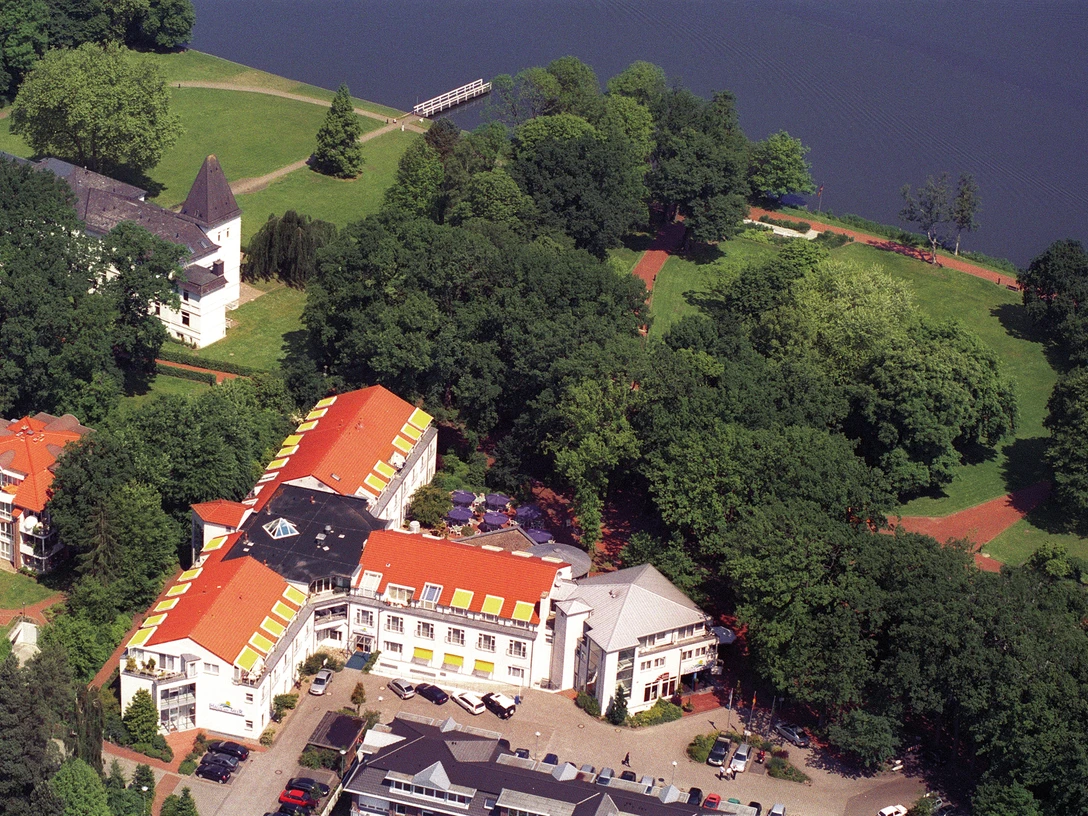 Haus am Meer Eine ruhige Landschaft mit grünen Bäumen umschließt ein Haus am Wasser im Sonnenschein.