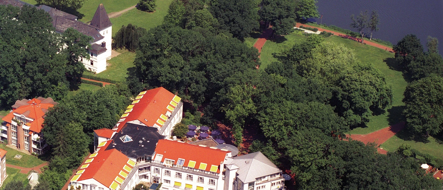 Haus am Meer Eine ruhige Landschaft mit grünen Bäumen umschließt ein Haus am Wasser im Sonnenschein.