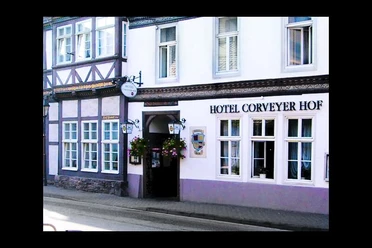 hotel-corveyerhof-hausansicht Fachwerkhaus mit Schild "Hotel Corveyer Hof" an der Fassade, Fenster mit Blumenkästen dekoriert.