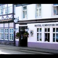 hotel-corveyerhof-hausansicht Fachwerkhaus mit Schild "Hotel Corveyer Hof" an der Fassade, Fenster mit Blumenkästen dekoriert.