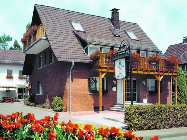 pension-zurweser-hausansicht Mehrstöckiges Gästehaus mit blühenden Balkonpflanzen und gepflegtem Vorgarten in einer ruhigen Wohngegend.