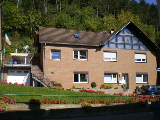 Ein zweistöckiges, modernes Ziegelhaus mit Satteldach, großen Fenstern und gepflegtem Vorgarten.