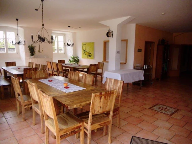 Heller Frühstücksraum mit mehreren Holztischen und -stühlen, dekoriert mit Pflanzen und Wandbildern.