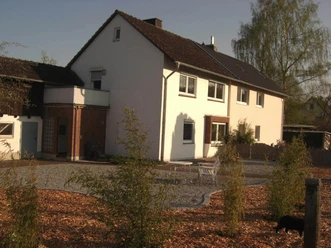 Hausansicht mit Kiesfläche und SträuchernHouse view with gravel area and shrubs