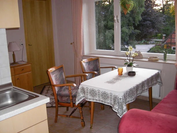 Küche Küche mit Spüle, Esstisch, zwei Stühlen und einer roten Sitzbank am Fenster.