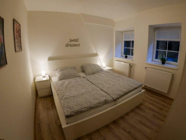 Schlafzimmer Weißes Doppelbett mit grauer Bettwäsche in hellem Schlafzimmer mit Holzfußboden.