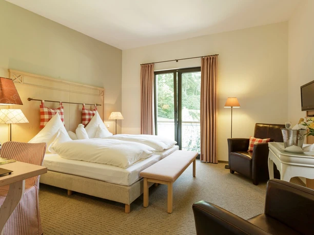 Zimmer im Landgasthof Mücke in Marsberg Geräumiges Landgasthof-Zimmer mit Doppelbett, Schreibtisch, Sesseln und einem großen Fenster mit Blick ins Grüne.