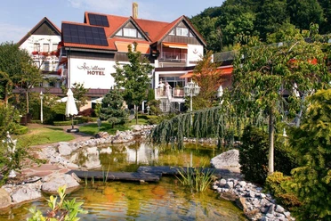 Ringhotel Teutoburger Wald****, Tecklenburg Brochterbeck Ringhotel Teutoburger Wald: Ein gepflegter Garten mit Teich und Brücke vor einem Hotelgebäude.