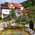 Ringhotel Teutoburger Wald****, Tecklenburg Brochterbeck Ringhotel Teutoburger Wald: Ein gepflegter Garten mit Teich und Brücke vor einem Hotelgebäude.
